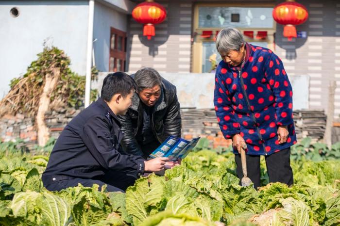 　江蘇省泰州市海陵區(qū)蘇陳派出所民警在蘇陳社區(qū)田間地頭向農(nóng)戶進行普法宣傳(2021年12月4日攝)。新華社發(fā)(湯德宏 攝)