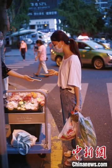 手提兩袋蔬菜的成都市民在選購鮮花?！∈茉L者供圖