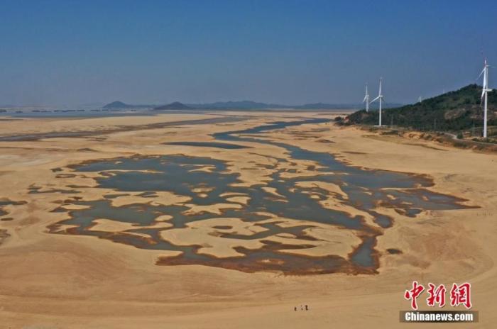 在江西省九江市都昌縣鄱陽(yáng)湖水域，干涸的湖床形成多個(gè)大小不同的水洼，幾名游客正在灘涂上行走。(資料圖) 劉占昆 　攝