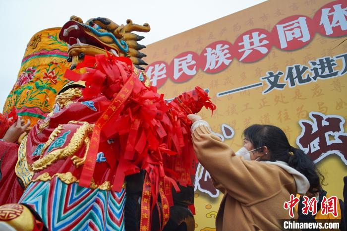 圖為市民將許愿帶綁在龍王塑像的座椅上祈福。　韋國(guó)政 攝