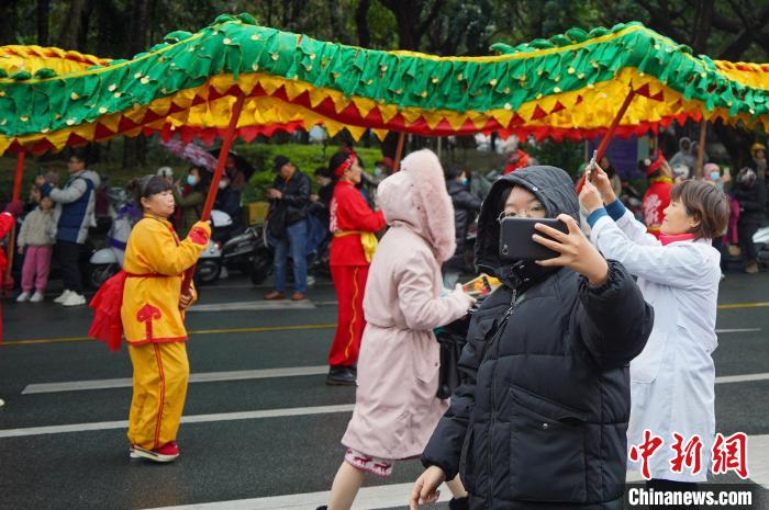 圖為一位市民站在巡游隊(duì)伍旁自拍合影?！№f國(guó)政 攝