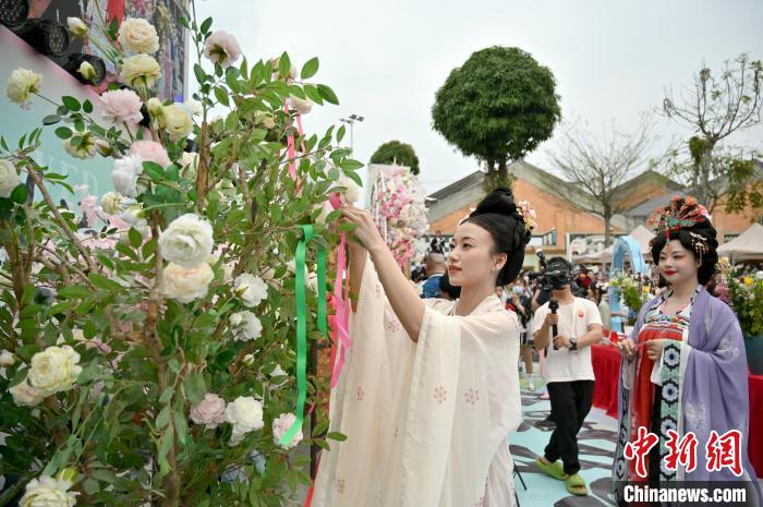 圖為漢服愛好者將彩帶掛在花枝上，蘊意美好?！∮峋?攝