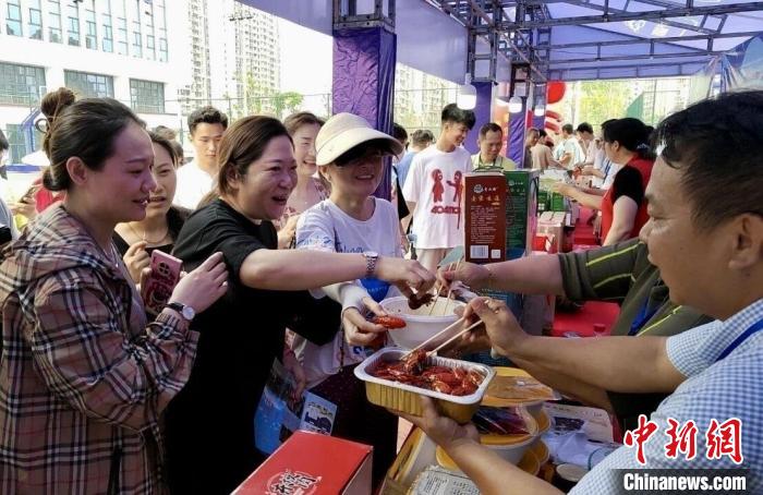 圖為江西南昌英雄城啤酒龍蝦燒烤節(jié)上，游客爭(zhēng)相品嘗鐵河小龍蝦預(yù)制菜?！⌒陆▍^(qū)融媒體中心供圖