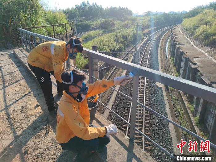 圖為高溫下南寧工務(wù)段橋梁工全副武裝對鐵路橋梁人行道欄桿打磨除銹。　馮博 攝