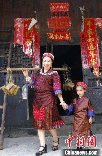 施秉縣楊柳塘鎮(zhèn)陸地坪苗寨苗族女同胞帶著包好的粽粑串門?！》盍?攝