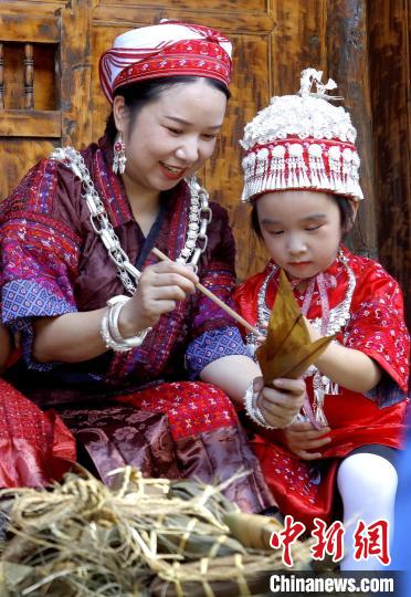 施秉縣楊柳塘鎮(zhèn)陸地坪苗寨一位苗族女子教孩子包粽粑?！》盍?攝